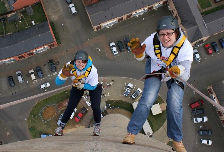Two people abseil down a high wall