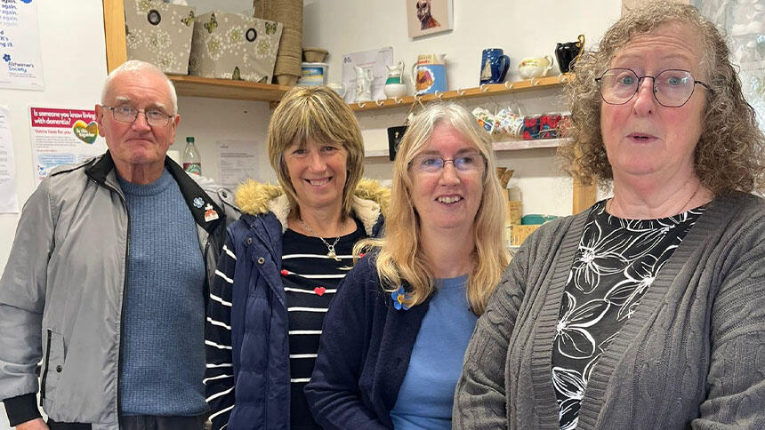 Four volunteers at the cafe stood in front of shelves.