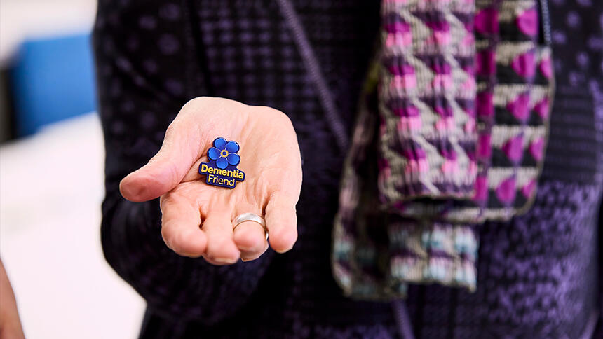 A Dementia Friends badge being held out in someone's open hand
