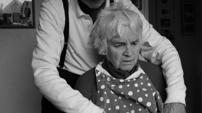 Kyra's grandad, Aubrey, helping Winnifred put on her apron