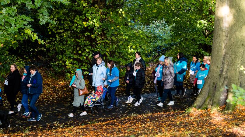 Group of people wearing Memory Walk t-shirts walking along woodland path
