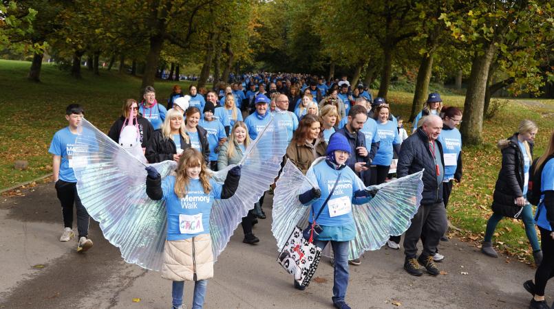 Participants at Manchester Memory Walk making their way around Heaton Park. The two walkers in the forefront have large light up butterfly wings on