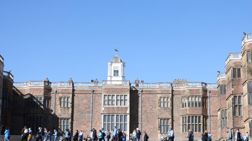 People wearing blue Memory Walk t-shirts, walking together in front of Temple Newsam House