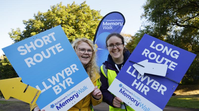 Two volunteers holding the long route and short route signs out on the route