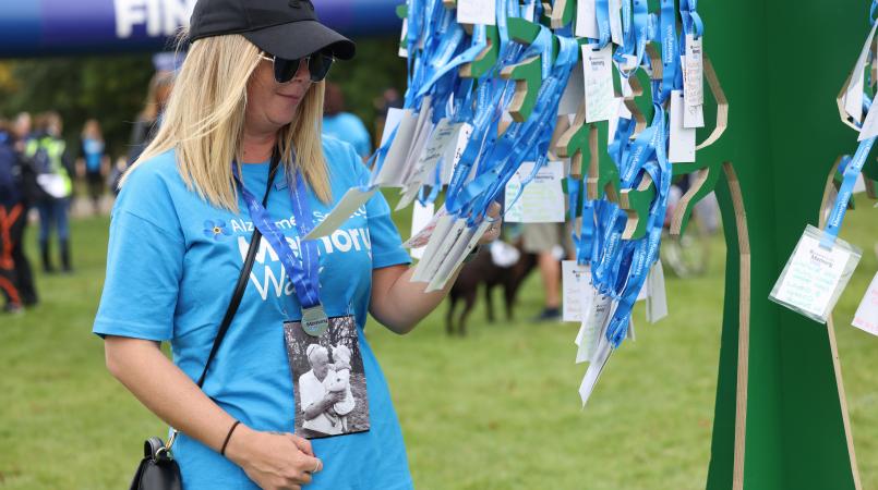 A lady in a Memory Walk top reading the tags on the Memory Tree