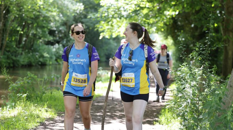 Two people walking along a tree lined path.