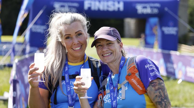 Two people smiling with a glass of prosecco and a medal.