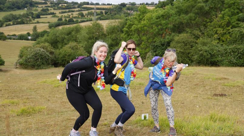 Three woman with fancy dress posing on a hillside.