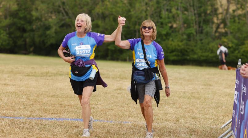 Two women holding hands as they cross the finish line.