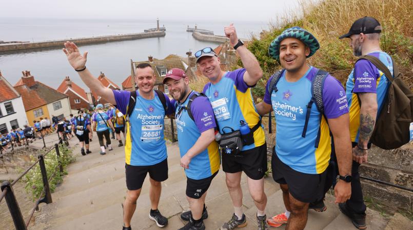 Group of men standing on steps cheering with the coast in the background.