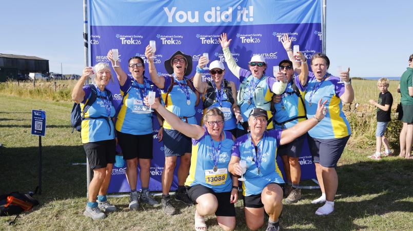 Group of people celebrating at a finish line with medals.
