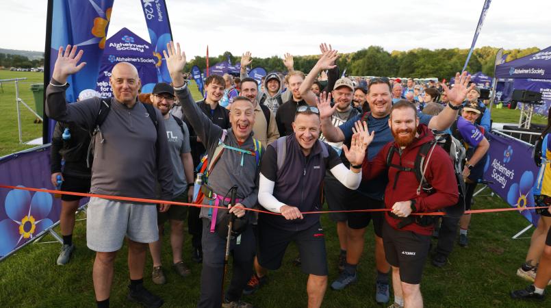 Group of people at a start line smiling and waving.