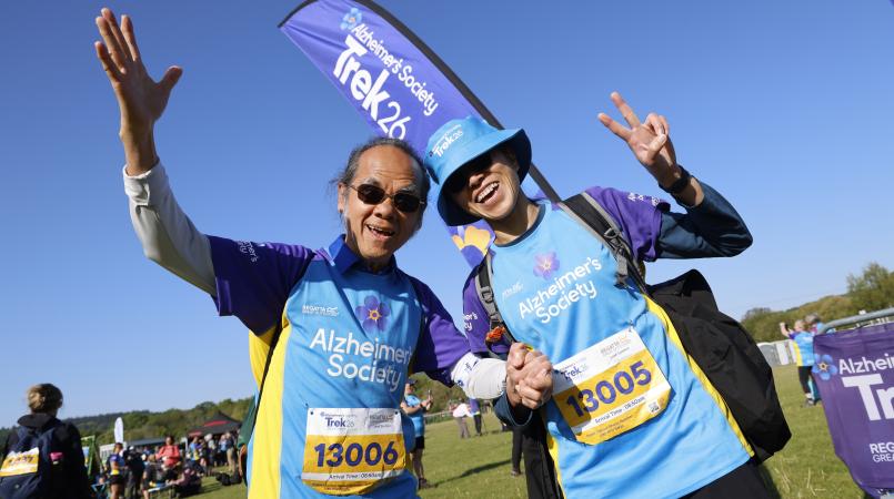 Man and woman posing in front of a Trek26 flag.