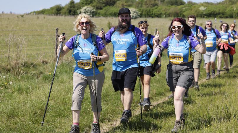 Group of people walking across a field smiling.