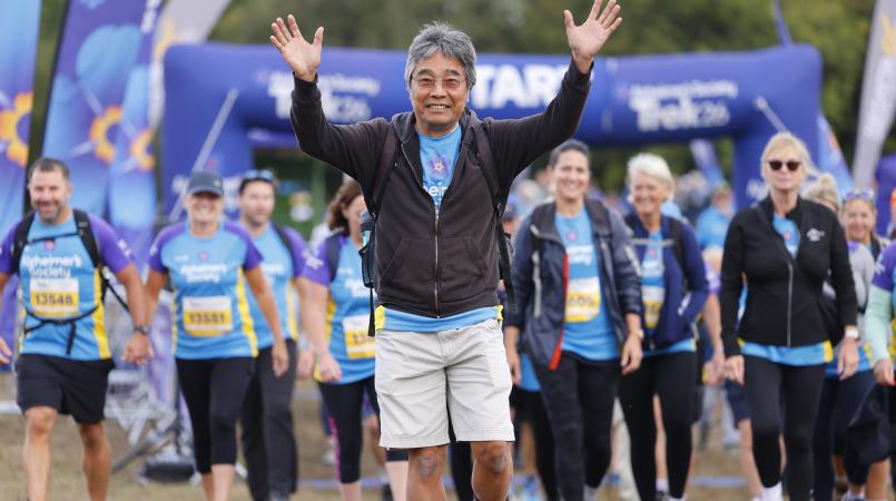 Man walking over a start line waving to friends and family.