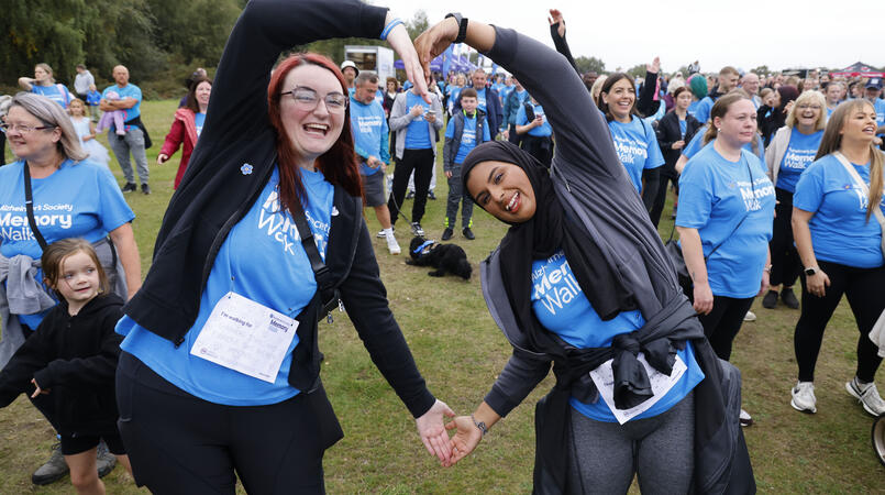 Two walkers in blue Memory Walk t-shirts form a heart with their arms
