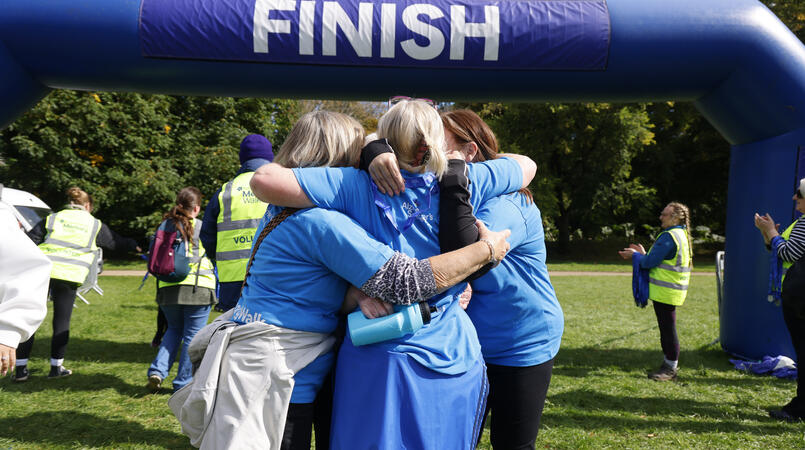 A group of walkers hug each other at the finish line