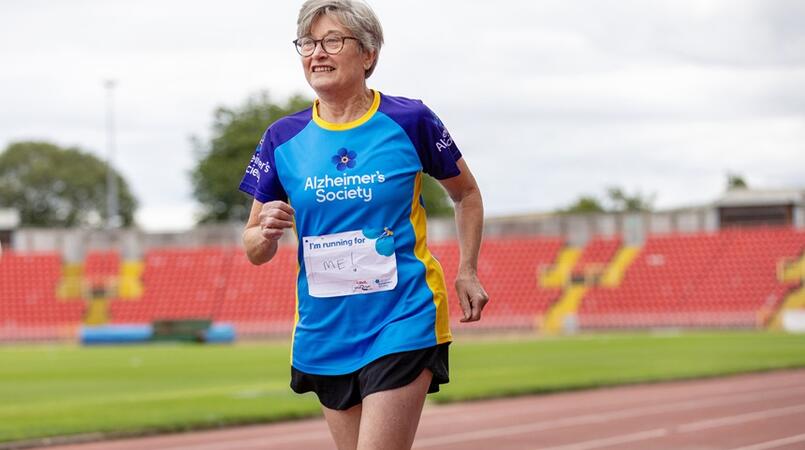 Woman running around an athletics track