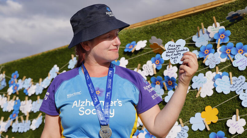 A person holding a flower card with an in memory message.